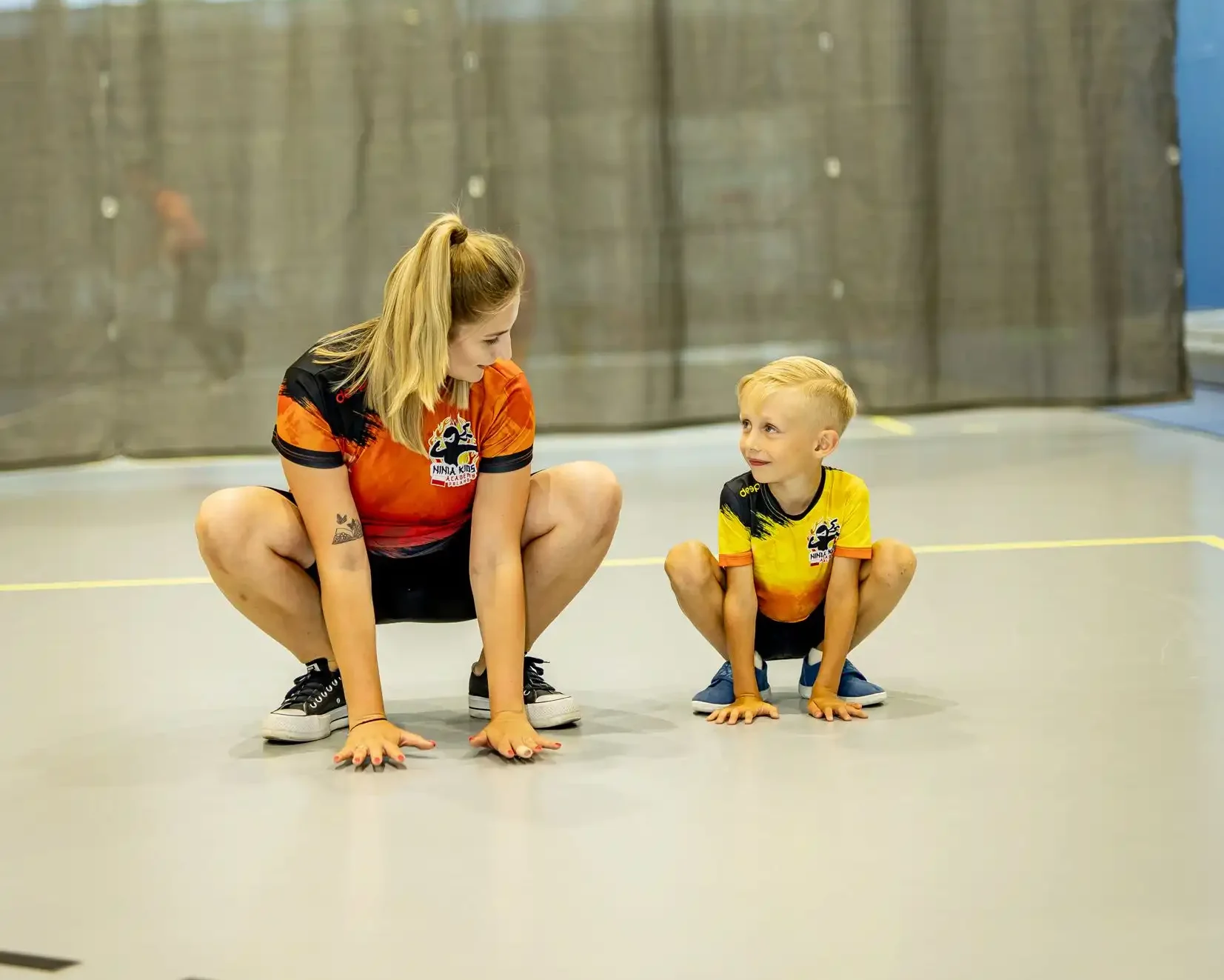 Trener i dziecko Ninja Kid uczący się przysiadów