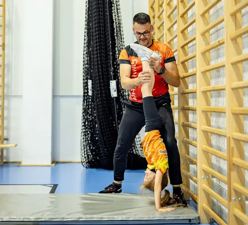 Wychowawca Ninja Kids Academy uczący dziecko stawać na rękach
